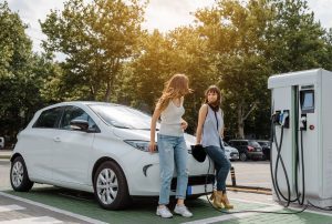 two women waiting to charge electric car