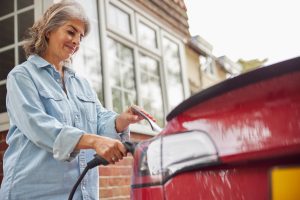 woman charging electric car at home