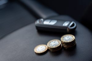 car key next to pound coins and saving money